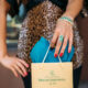 Photo of a female with an emerald ring and bracelet holding an emeralds international shopping bag.