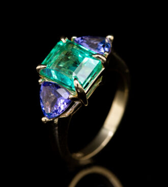 Emerald & Tanzanite Ring on a black background.
