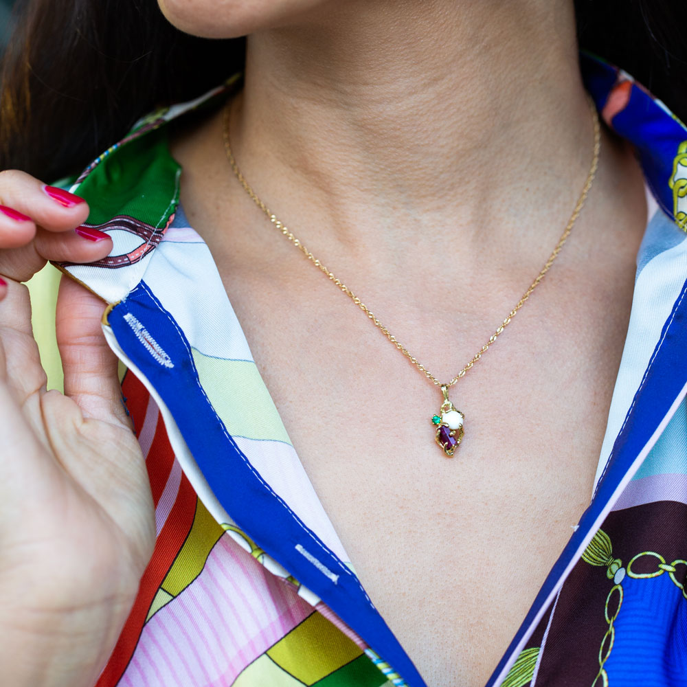 Red Beryl, Conch Pearl & Emerald Pendant on a model with a colorful shirt.